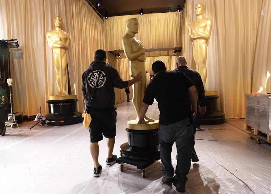 Los trabajadores transportan una estatua del Oscar en la alfombra roja durante los preparativos./ EFE